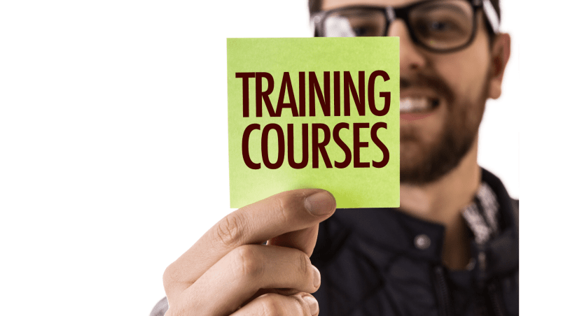 Post-it note saying "Training Courses" held up by a man, promoting IT and tech training programs at MyComputerCareer with a focus on career development and certification.