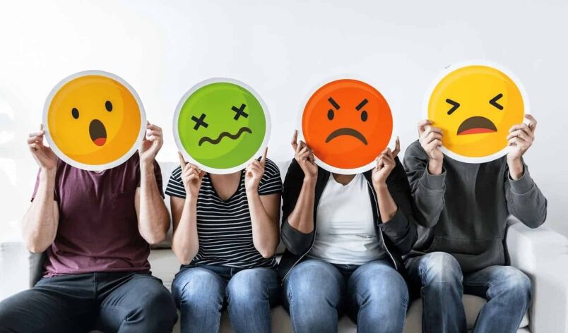 Happy students holding emoji masks representing various emotions in a classroom or training environment, promoting positive learning experience at MyComputerCareer.