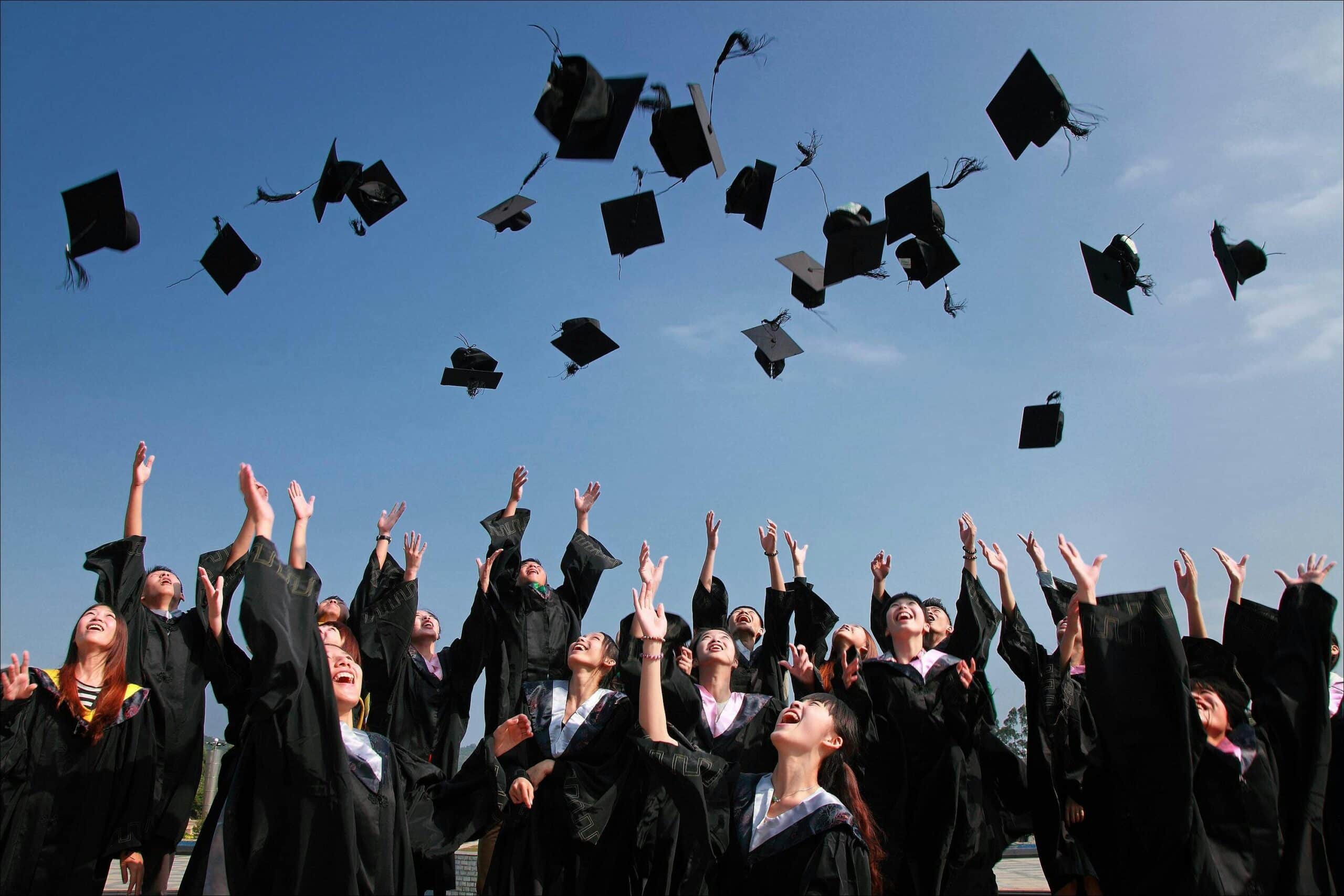 Graduates in caps and gowns celebrating their graduation day outdoors, symbolizing achievement, success, and new careers in technology and IT fields.