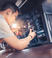 Computer technician working inside a desktop PC, repairing or upgrading hardware, emphasizing IT support, computer repair, and technical skills training.