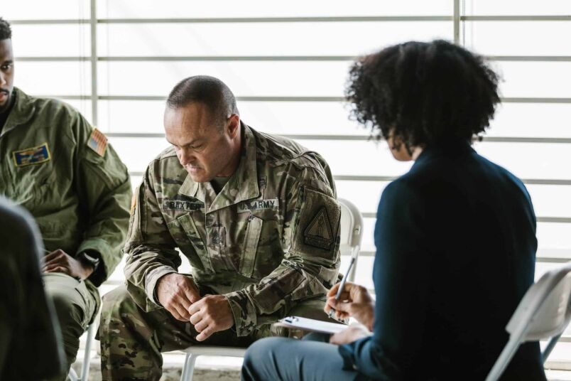 Veteran in military uniform attending a counseling session with a civilian woman for mental health support; represents military veterans, mental health, and veteran services.