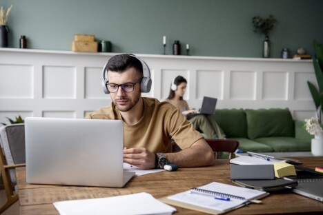 Computer student studying technology at a desk with laptop and headphones, focusing on IT training and online education, emphasizing computer careers.